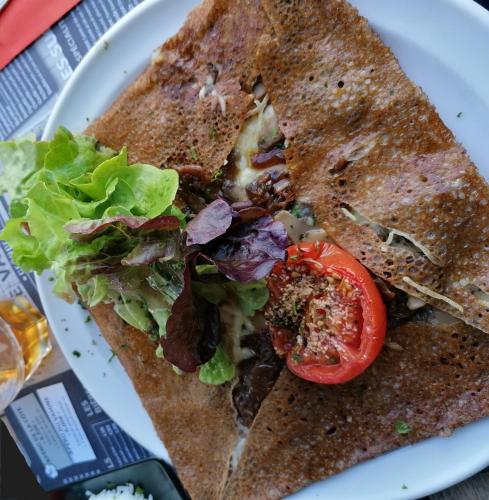 a sandwich with a salad and a tomato on a plate at Loctycaz Appartement avec jardin in Locmariaquer