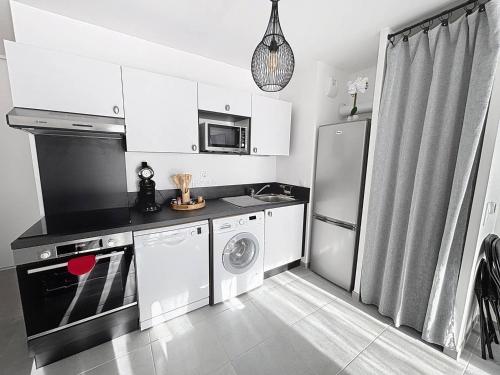 une cuisine avec des armoires blanches et une laveuse et une sécheuse dans l'établissement Charmant appartement proche plage avec balcon et parking privé - FR-1-465-123, à Cabourg