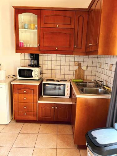 a kitchen with wooden cabinets and a sink and a microwave at Skandalis Apartments with pool in Chorafakia
