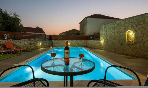 a table with two glasses of wine next to a swimming pool at Skandalis Apartments with pool in Chorafakia