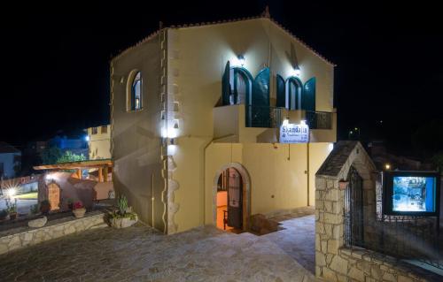 a large yellow building with a clock tower at night at Skandalis Apartments with pool in Chorafakia