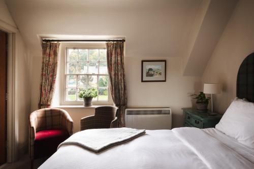 a bedroom with a bed and a window and a chair at The Pilsley Inn - Chatsworth in Baslow