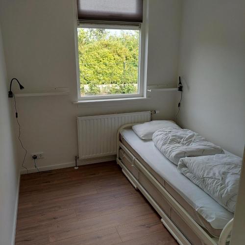 a small bedroom with a bed and a window at De Dopheide | 4 persons in Gasselte