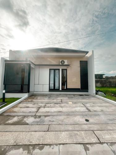 a small white house with a driveway at Villa Kamar Tamu Concat in Yogyakarta