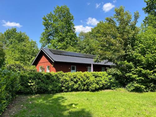 a red house with a black roof and some trees at Bungalow De Babbel | 4 persons in Gasselte