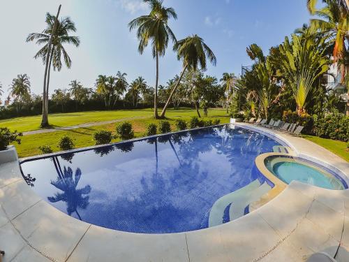 a swimming pool in a resort with palm trees at Acogedor depto Acapulco Diamante frente a campo de Golf Vidanta in Acapulco