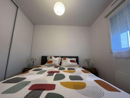 une chambre avec un lit avec une couette colorée dans l'établissement Appartement chaleureux proche du centre et de la plage, à Crozon