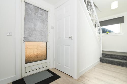 a hallway with a white door and a window at 4 Bedrooms-2Bath-Free Parking in Dunipace