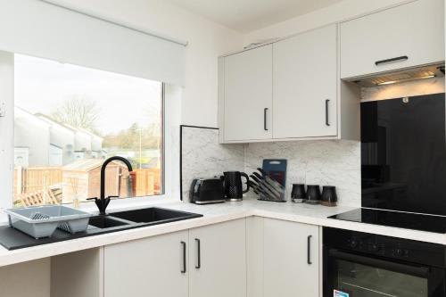 a kitchen with white cabinets and a sink and a window at 4 Bedrooms-2Bath-Free Parking in Dunipace