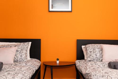 two pillows and a table in front of an orange wall at 4 Bedrooms-2Bath-Free Parking in Dunipace