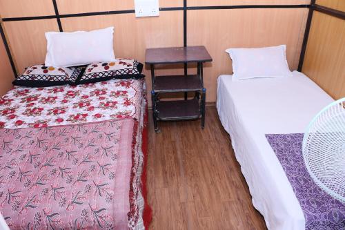 a small room with two beds and a table at Jungleparadiso Homestay in Thekkady