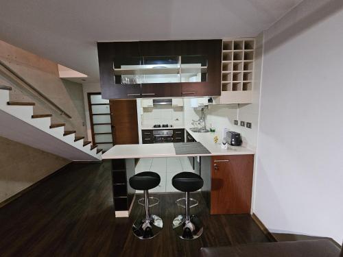 a kitchen with a counter and two stools in it at Departamento amoblado Lomas San Andres in Concepción