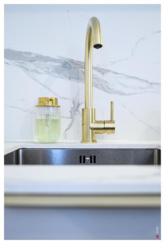d'un évier avec un robinet en or. dans l'établissement Entre Paris et le Chateau de Versailles - Parking, à Rueil-Malmaison