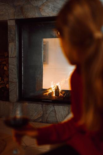 a woman is looking at a fire in a fireplace at Alpina Alpendorf in Sankt Johann im Pongau