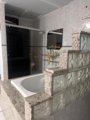 a bathroom with a bath tub and a mirror at Aconchego by the lagoon in Araruama