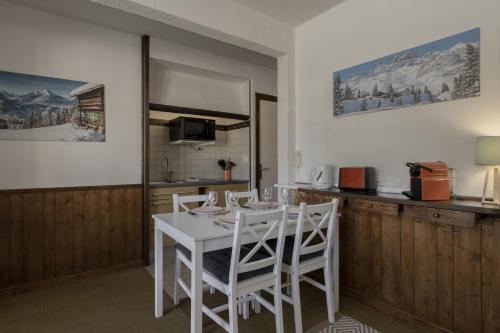 - une cuisine avec une table blanche et des chaises blanches dans l'établissement Le Miage, à Chamonix-Mont-Blanc