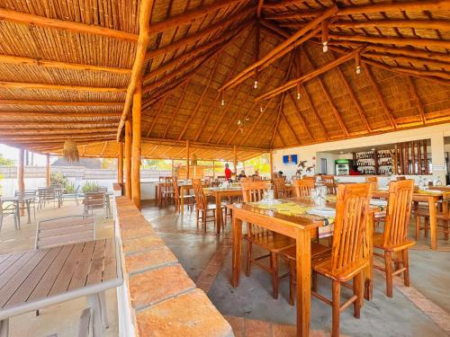a dining room with wooden tables and chairs at Telvina Beach Lodge in Vilanculos