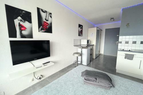 un salon avec une télévision à écran plat sur un mur dans l'établissement Naturiste Cap d'Agde Héliopolis F 47, au Cap d'Agde