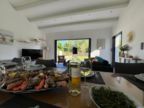 - une table avec une assiette de nourriture et une bouteille de vin dans l'établissement New Rethaise holiday home 8 people, au Bois-Plage-en-Ré