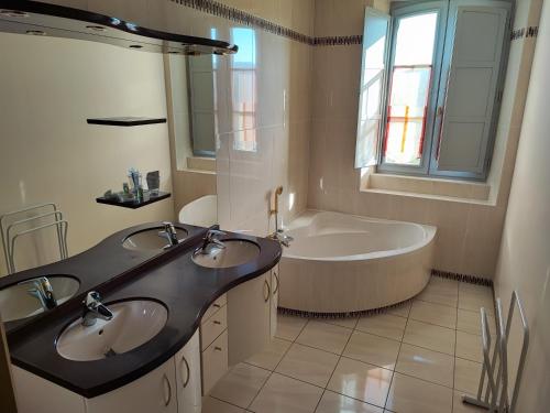 une salle de bain avec deux lavabos et une baignoire dans l'établissement MAISON DE CHARME LES CAILLAVES, à Limeuil