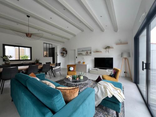 un salon avec des canapés bleus et une salle à manger dans l'établissement New Rethaise holiday home 8 people, au Bois-Plage-en-Ré