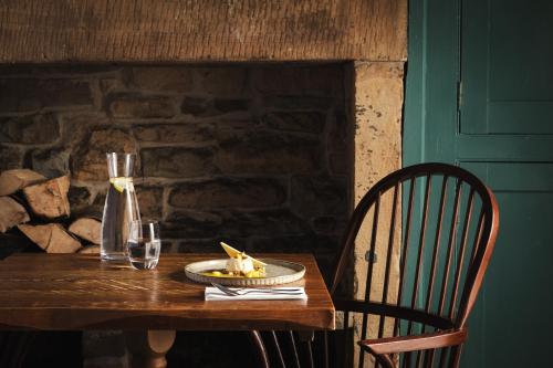 a wooden table with a plate of food and a vase at The Pilsley Inn - Chatsworth in Baslow