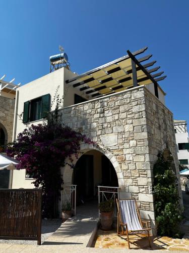 a building with a stone wall and two chairs at Villa Elpida Aspro in Koprána