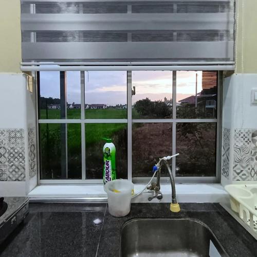 a kitchen sink with a window with a view of a field at Ebnur Homestay in Arau