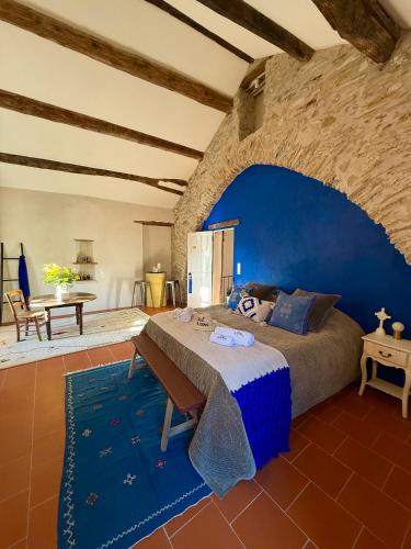 une chambre avec un grand lit avec un mur bleu dans l'établissement Ostal de la Croix Vieussan, à Vieussan