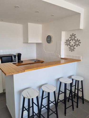 une cuisine avec trois tabourets de bar à un comptoir dans l'établissement Naturiste Cap d'Agde Port Ambonne 204, au Cap d'Agde