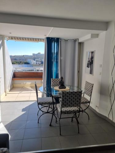 une salle à manger avec une table et des chaises en verre dans l'établissement Naturiste Cap d'Agde Port Ambonne 204, au Cap d'Agde