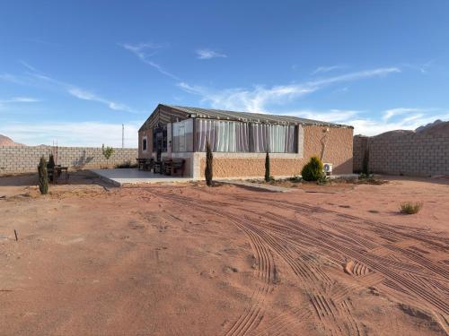 a building in the middle of a desert with a dirt road at Wadi Rum Marina Camp in Wadi Rum