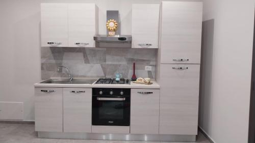 a kitchen with white cabinets and a stove and a sink at Il Calice dell'Etna in Passopisciaro