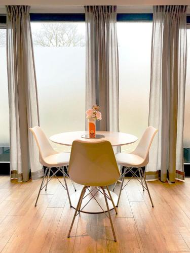 a table and chairs in a room with windows at De bank van Nagele in Nagele