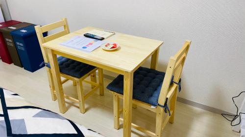 a small wooden table and two chairs and a book at 新所沢駅徒歩1分 近くに豊富な飲食店 ベルーナドーム 東京や川越観光拠点に コンビニ30秒 in Tokorozawa