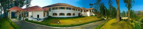 a large white house with a large yard at Tea county in Munnar