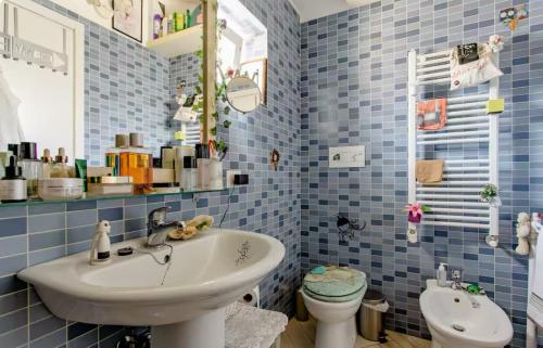 Un baño con azulejos azules, lavabo e inodoro. en Stanza relax con uscita sulla spiaggia, en Focene