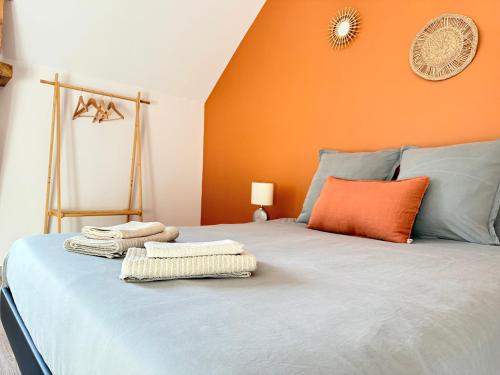 un lit avec des serviettes dessus avec un mur orange dans l'établissement Le 449 - Portes de Bayeux, à Bayeux