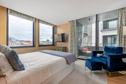 a bedroom with a large bed and a blue chair at Jacuzzi, Terrace & Infinity Pool at Savoy Insular in Funchal