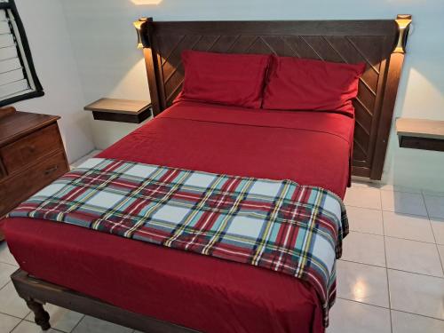 a bed with red sheets and red pillows at Mom's Place Negril in Negril