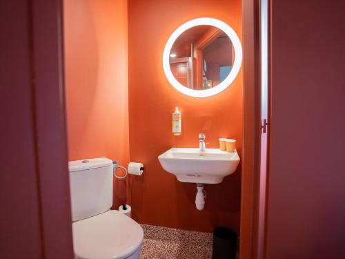 a bathroom with a toilet and a sink and a mirror at Greet hôtel Montpellier Aéroport Parc des Expos in Mauguio