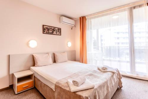 a bedroom with a bed and a large window at Aparthotel Hotel Prestige City II in Primorsko