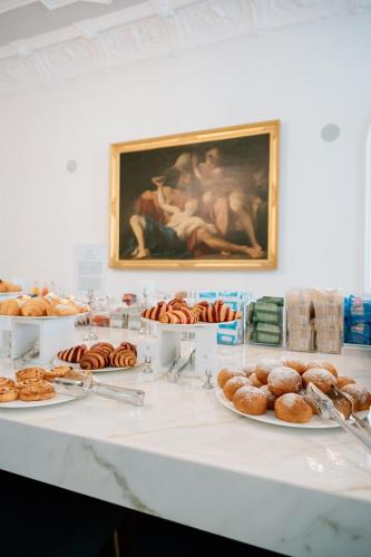 a table with plates of donuts and a painting at Grand Hotel Victoria concept & spa, by R Collection Hotels in Menaggio