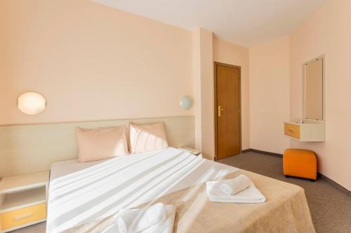 a bedroom with a large white bed with pink pillows at Aparthotel Hotel Prestige City II in Primorsko