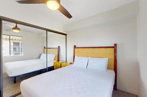 a bedroom with a white bed and a mirror at Pacific Shores A402 in Kihei