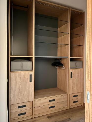 a wooden closet with wooden doors and empty shelves at Humanitas & Forum - CASA TUA Housing in Rozzano