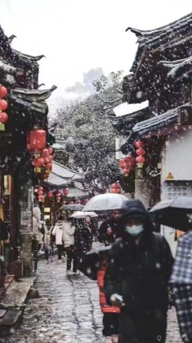 a group of people walking down a street in the snow at Lijiang Old Town Meiliju View Inn in Lijiang