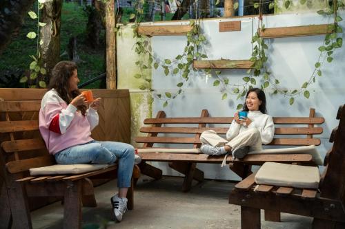 two women sitting on benches looking at their cell phones at Casa Profunda - Santa Elena in Medellín