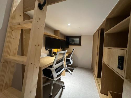 a small room with a desk and a computer and shelves at Nomad Live Hostel in Busan