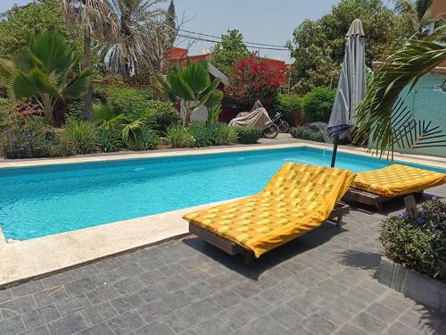 a pool with two beds and an umbrella next to it at Villa de luxe avec piscine au soleil du sénégal petite cote in Mbour